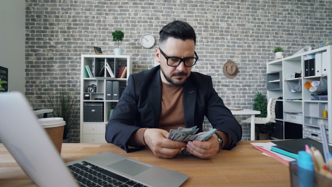 A professional interior architect works on a laptop at a clean, modern desk in a well-lit, stylish office, planning a new design.