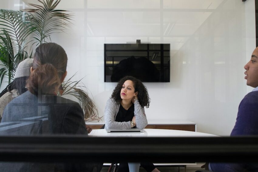 Diverse group of technology leaders in business attire collaborating around a conference table in a modern, brightly lit o...